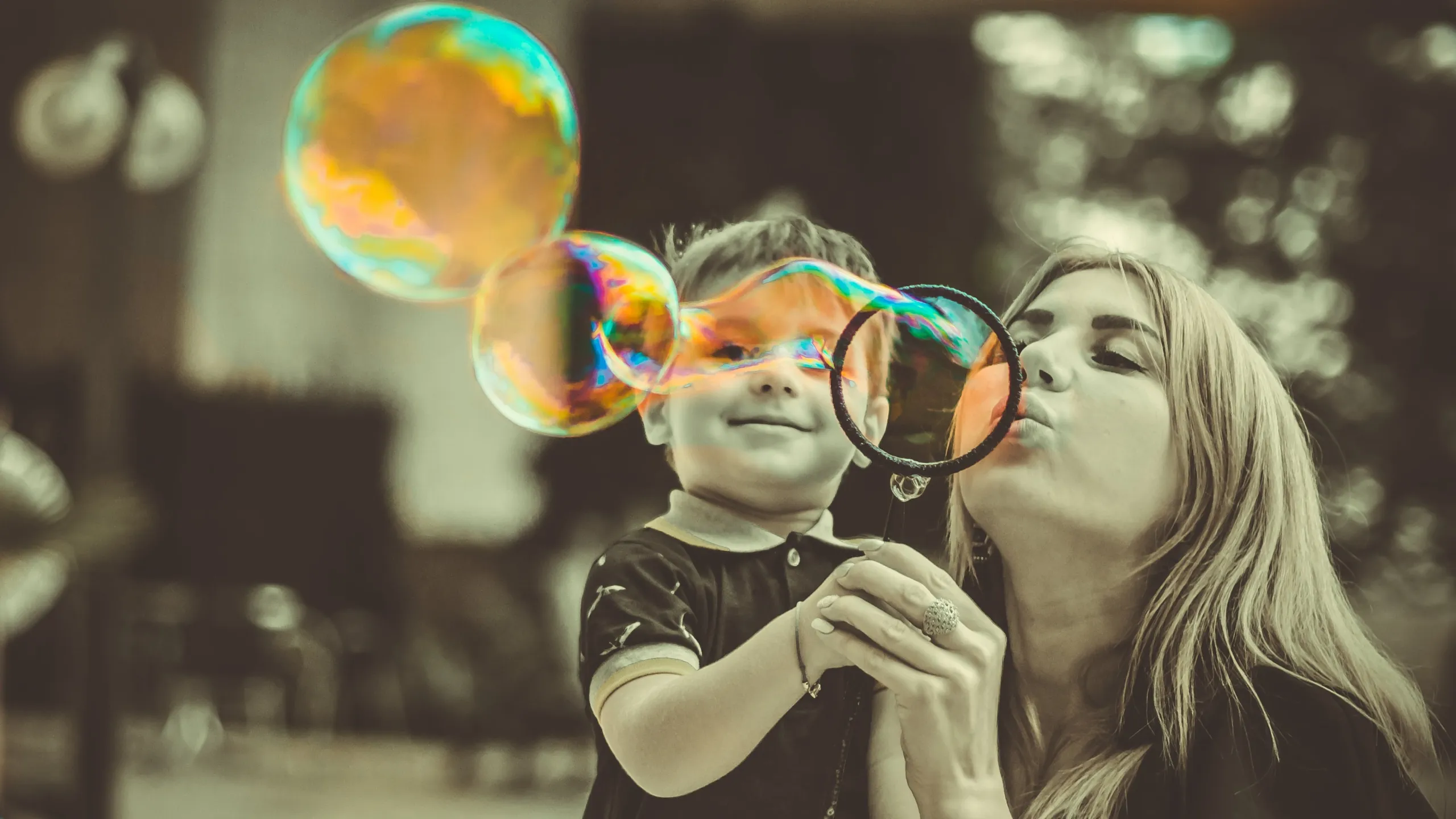 A mother and her young son blowing bubbles together