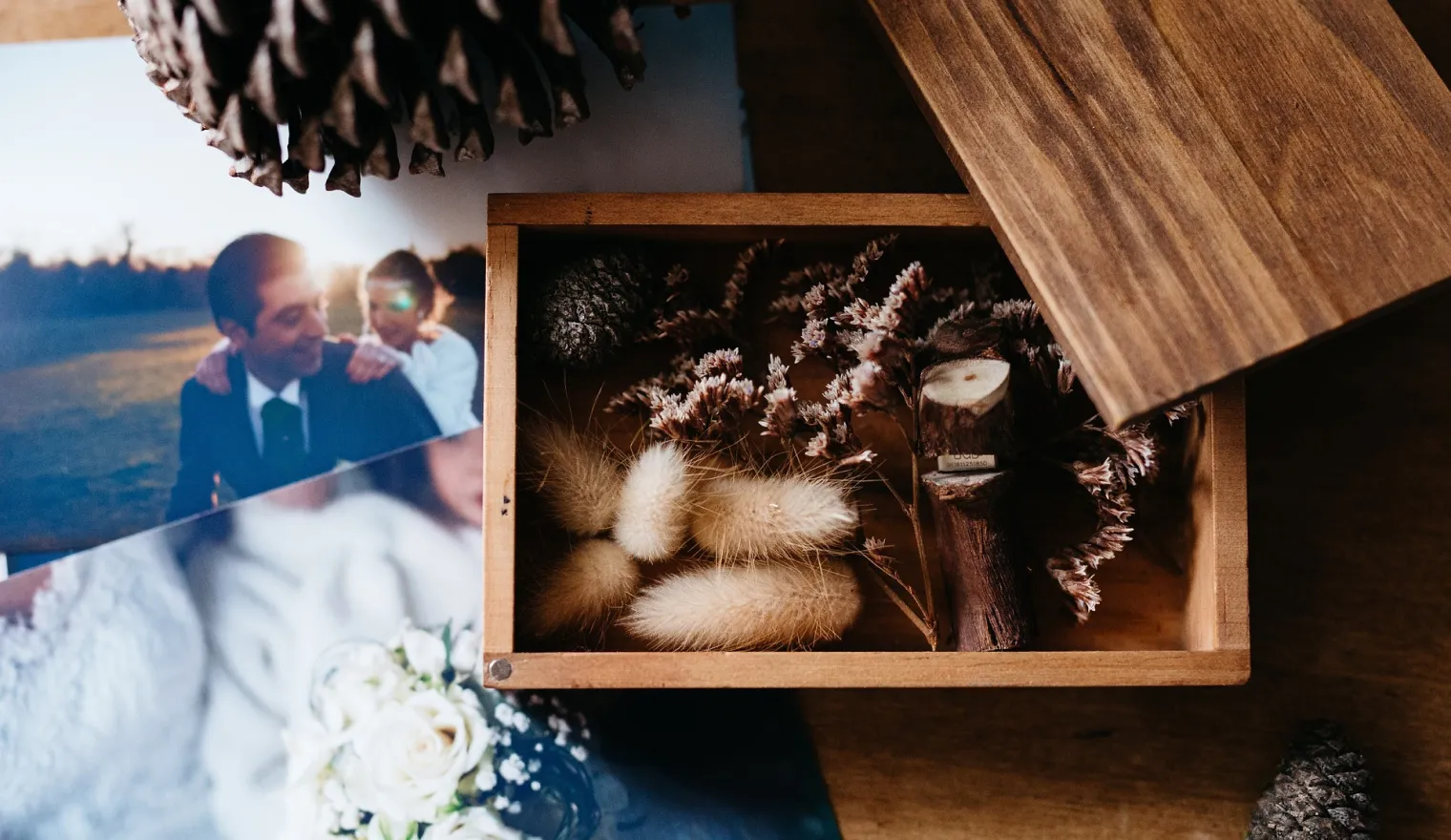 A wooden keepsake box of dried flowers beside family wedding photos