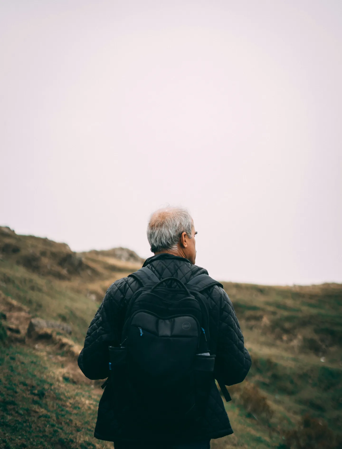 A man walking alone across a misty hillside