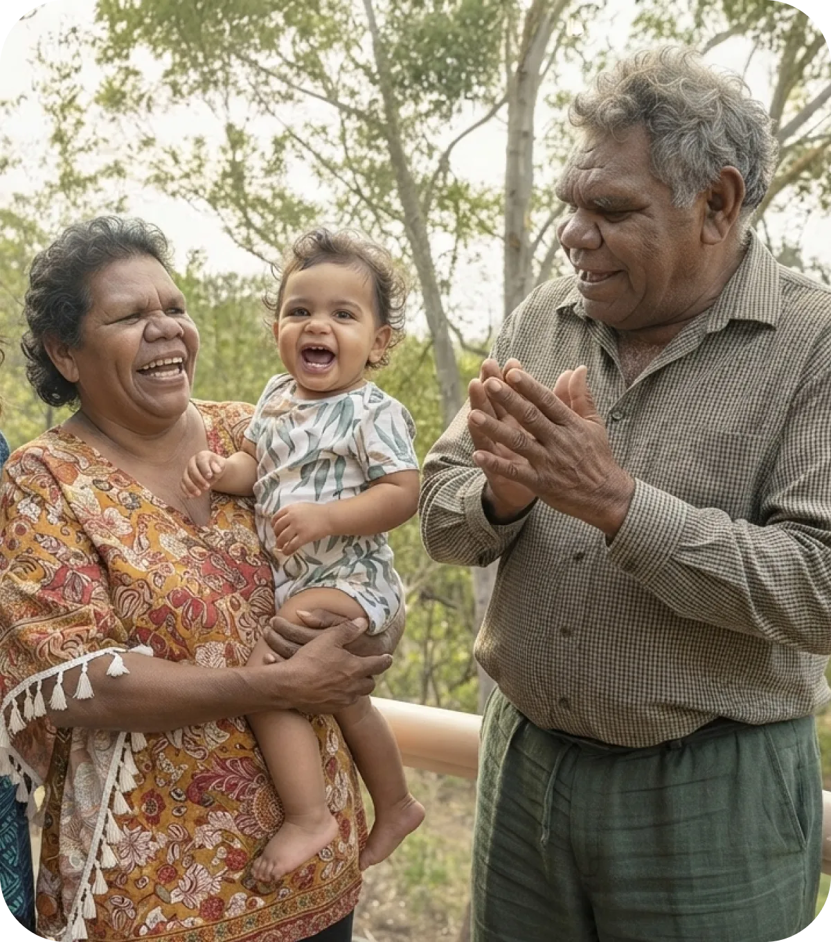 A grandmother and grandfather laughing with their grandchild outdoors